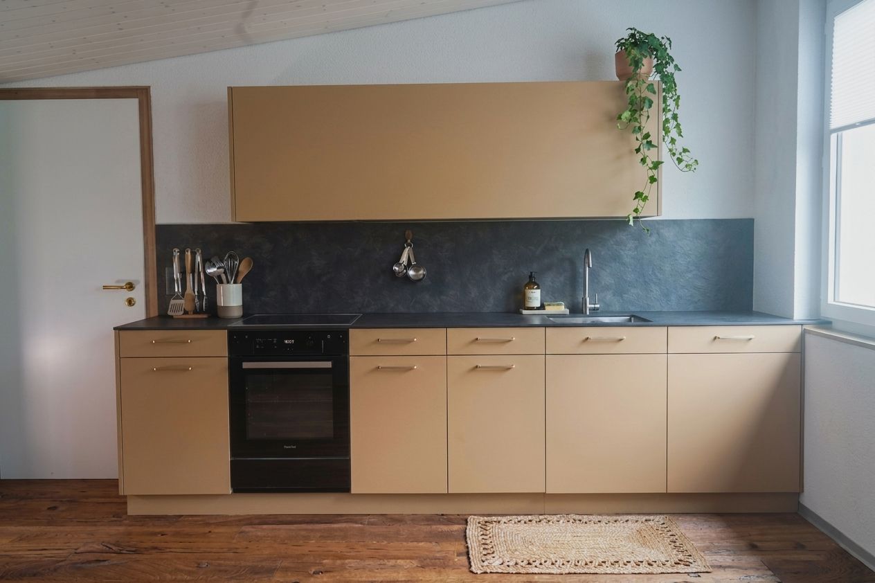 Studio-Küche mit sandfarbenen Fronten und Messinggriffen – Küchenbau Schreinerei Moser Holzhandwerk Thun Belp